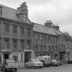 View of south elevations of 10 -16 Canongate, Jedburgh from west, showing the premises of John Luhn & Son, Matthew C Noble and J C Clark & Co