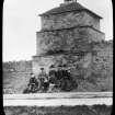 View of dovecot possibly in Aberlady with a group of seven adults and a child posing for the photograph in the foreground.
