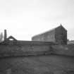 General view of works from NE, showing boiler-house chimney and E side of high mill, with N side of single-storyed shed.