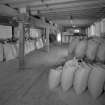 Interior view from W on first floor of central bay of granary, showing sacks of barley