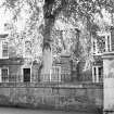 General view of the front facade partially obscured by foliage seen from the North North West.