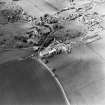Oblique aerial view centred on the farmsteadings, church and burial ground with village adjacent, taken from the SSE