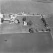 Oblique aerial view from W with farm buildings to N.