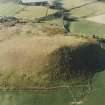 Oblique aerial view centred on the remains of the fort with the remains of the cottage, huts and sheepfold adjacent, taken from the SSW.