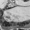 Oblique aerial view of Kinghornie centred on the cropmarks of possible graves with a house and farmsteading and cropmarks of round-houses, a possible souterrain, pits and a possible enclosure adjacent.  In addition, there are the remains of a pillbox and anti-tank blocks on the shore. Taken from the S.