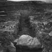 Cairnpapple Hill, photograph of excavation showing kerb stones of Period III cairn on W with henge ditch beyond.