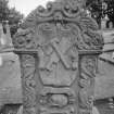 View of gravestone commemorating Henry Kedslie in the churchyard of Tranent Parish Church.Tranent churchyard, showing Green Man and cornucopia at top, crossed butchers tools, 'Memento Mori' scroll, skull and single bone at foot of stone.