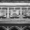 Detail of shields over bay window on right of S front.