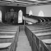 Interior. Gallery  view from S showing curved raked pews