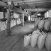 Interior view from W on first floor of central bay of granary, showing sacks of barley