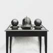 Photograph of 16th - 17th century helmet and 2 cannonballs displayed on table
