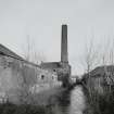 General view from S of works, showing Brothock Burn, and E end of boiler house and associated chimney.