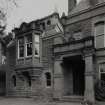 Detail of W entrance front showing porch, billiard room oriel and 1890 date stone