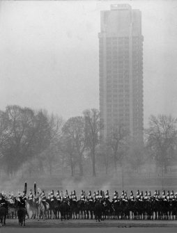 View of Married Quarters, Tower Block (Block F), Hyde Park Cavalry Barracks, London from Hyde Park with parade in foreground.
