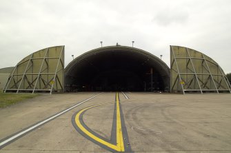 View.  Dispersal site hardened bombproof aircraft shelter with doors open from E.