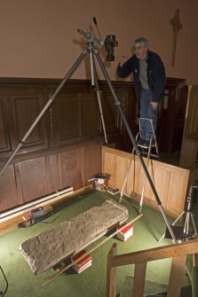 Interior view of Logierait Parish Church showing Mr S Wallace, RCAHMS, photographing Pictish cross slab