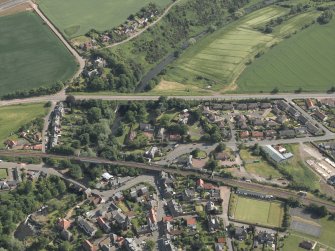 Oblique aerial view of the village centred on the road and rail bridges, taken from the N.