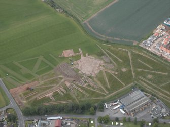 Oblique aerial view centred on the excavation of the enclosures, rig and other features, taken from the S.
