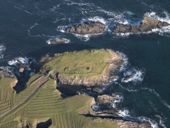 Oblique aerial view centred on the remains of the island settlement with the remains of lazy beds adjacent, taken from the S.