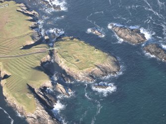 Oblique aerial view centred on the remains of the island settlement with the remains of lazy beds adjacent, taken from the SW.