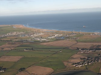 General oblique aerial view looking across the village towards the gas terminal, taken from the SW.