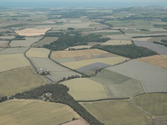 General oblique aerial view looking across the farmhouse and farmsteading to the East Lothian plain, taken from the SW.