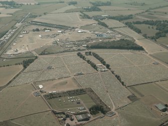 General oblique aerial view of the remains of the airfield and T in the Park, taken from the E.