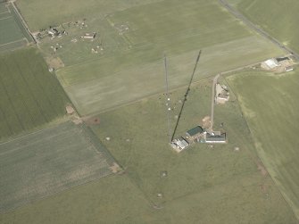 Oblique aerial view centred on the remains of the radar station, pillboxes and the mast, taken from the SW.