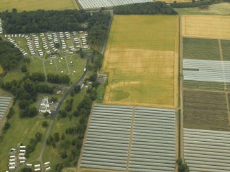 Oblique aerial view centred on the cropmarks of the rig, quarry and enclosure with the country house adjacent, taken from the SE.