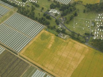 Oblique aerial view centred on the cropmarks of the rig, quarry and enclosure with the country house adjacent, taken from the NE.