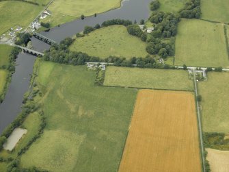 Oblique aerial view centred on the cropmarks and parchmarks of the Roman Fort with the bridge and dam adjacent, taken from the SE.