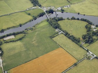 Oblique aerial view centred on the cropmarks and parchmarks of the Roman Fort with the bridge and dam adjacent, taken from the ENE.