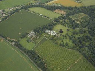 Oblique aerial view centred on the country house, castle, stables, lodge and walled garden, taken from the WSW.