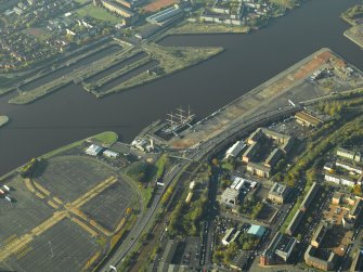 General oblique aerial view centred on the tall ship and wharf, taken from the NE.