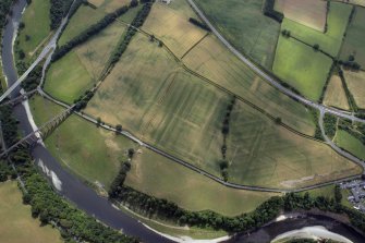 General oblique aerial view centred on the cropmarks of the Roman fort, Roman temporary camps and fort annexes with the railway viaduct adjacent, taken from the N.