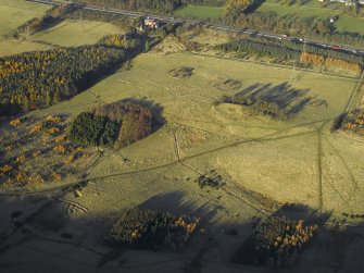 Oblique aerial view centred on the remains of the practice trenches with the farmhouse, farmsteading and cottages adjacent, taken from the SE.