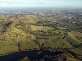 General oblique aerial view centred on the rifle ranges, farmhouse and farmsteading and the remains of the rig, fort, cultivation terraces and palisaded settlement, taken from the SW.