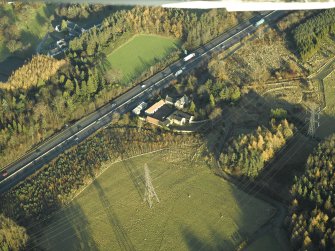 Oblique aerial view centred on the farmhouse, farmsteading and cottages, taken from the SW.