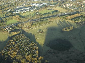 General oblique aerial view centred on the remains of the practice trenches with the farmhouse, farmsteading and cottages adjacent and the barracks in the distance, taken from the SW.