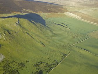 Oblique aerial view centred on the remains of the cultivation terraces, rig and sheepfold, taken from the SSW.