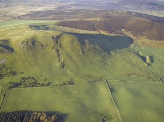 Oblique aerial view centred on the remains of the cultivation terraces, rig and sheepfold, taken from the SE.