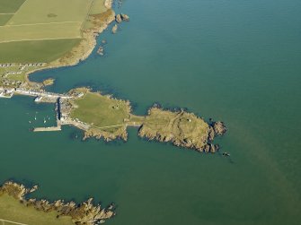 Oblique aerial view centred on the remains of the promontory fort and the chapel, taken from the SW.