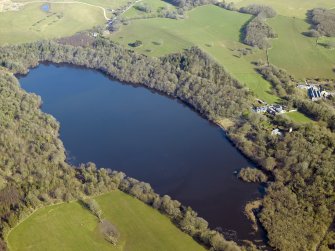 General oblique aerial view centred on the remains of the crannog and castle, and the cottage and offices, taken from the SW.