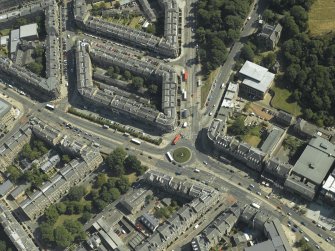 Oblique aerial view centred on the bank and tenements with the school and church adjacent, taken from the W.