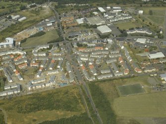 General oblique aerial view centred on the construction of the housing scheme with the school adjacent, taken from the SE.