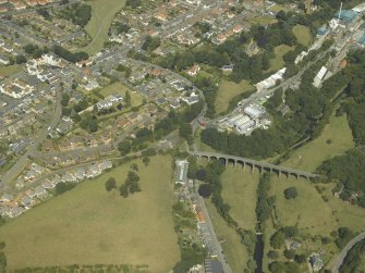 General oblique aerial view of the town centred on the railway viaduct, hotel and church with the house adjacent, taken from the SSW.