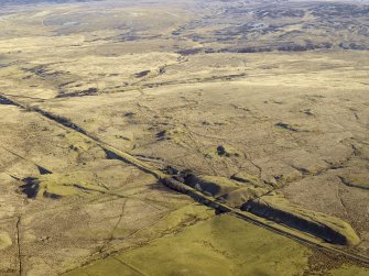 Oblique aerial view centred on the remains of the coal mines, bell pits and dismantled railway, taken from the NW.