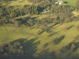 Oblique aerial view centred on the remains of the rig with the stables and country house adjacent, taken from the SSE.
