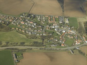 General oblique aerial view of the village, centred on the church, burial-ground and churchyard with the hotel and stable adjacent, taken from the SE.