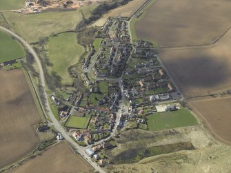 General oblique aerial view of the village, centred on the church, burial-ground and churchyard with the hotel and stable adjacent, taken from the NE.